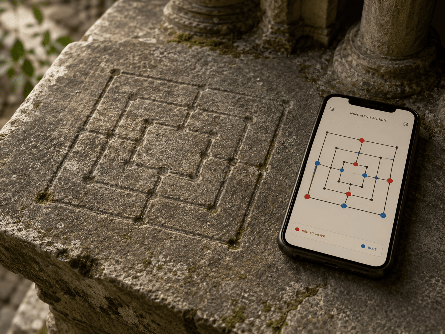 A weathered gray stone surface - the worn step of an old cloister - with a Nine Men's Morris board pattern of three nested squares deeply carved into it, centuries-smoothed. Resting on the stone beside the carving, a modern smartphone displays the same three-nested-squares board as a crisp minimalist app with red and blue pieces mid-game. Soft natural light, moss in the stone's cracks, quiet contrast of ancient and contemporary, warm tones with soft red and blue accents.